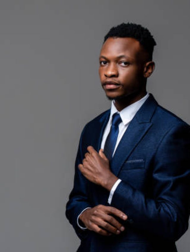 Portrait of young handsome African man wearing formal business suit looking at camera isolated on studio gray background